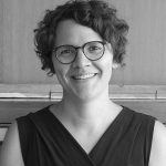 Black and white photo of a woman with short hair and glasses smiling at the camera