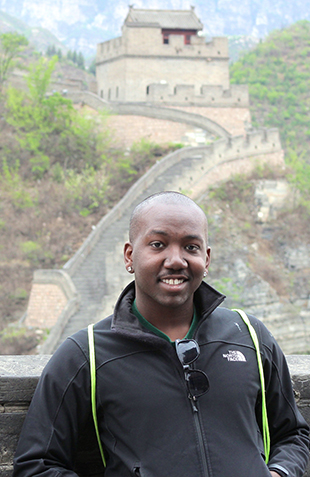 man posing in front of the great wall of china