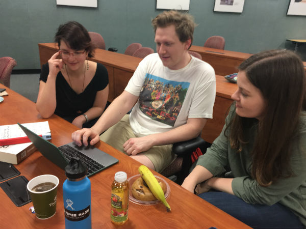 three students all staring at a laptop
