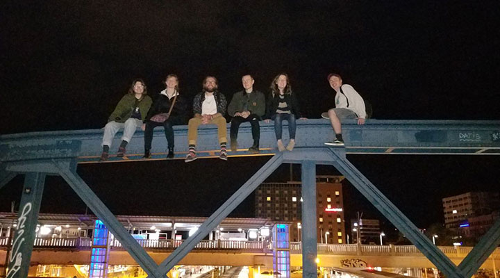 a group of 6 students all sitting on a bridge at night