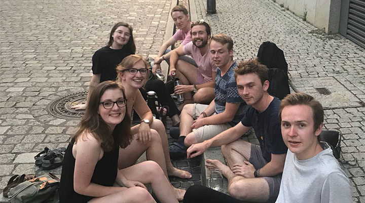 a group of 8 students all sitting on a sidewalk
