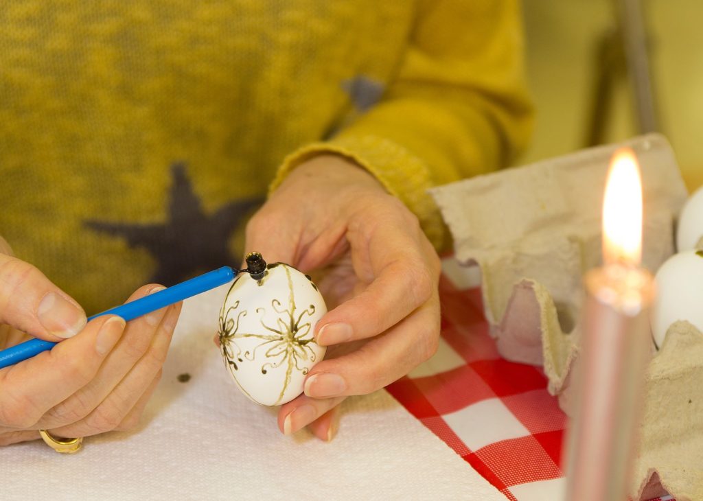Workshop participant making a Ukrainian Easter egg by putting beeswax on the egg with a stylus called a kistka