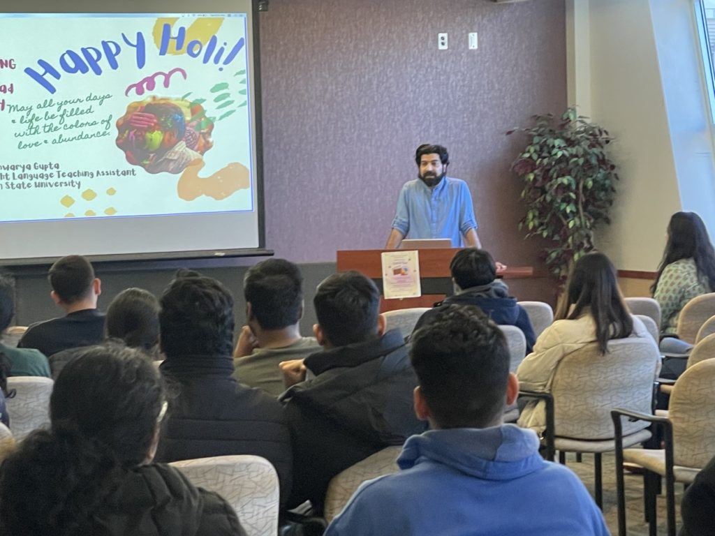 Presentation with "Happy Holi!" and Rajiv Ranjan speaking to a group of students