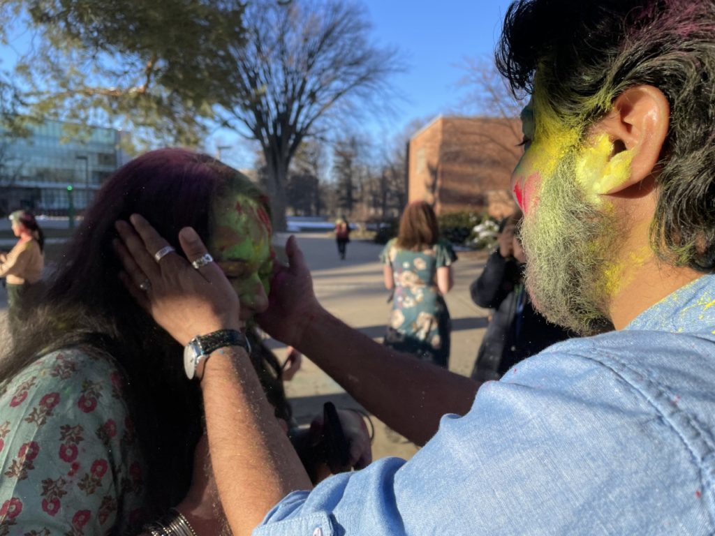 man on right putting colors on a woman's face